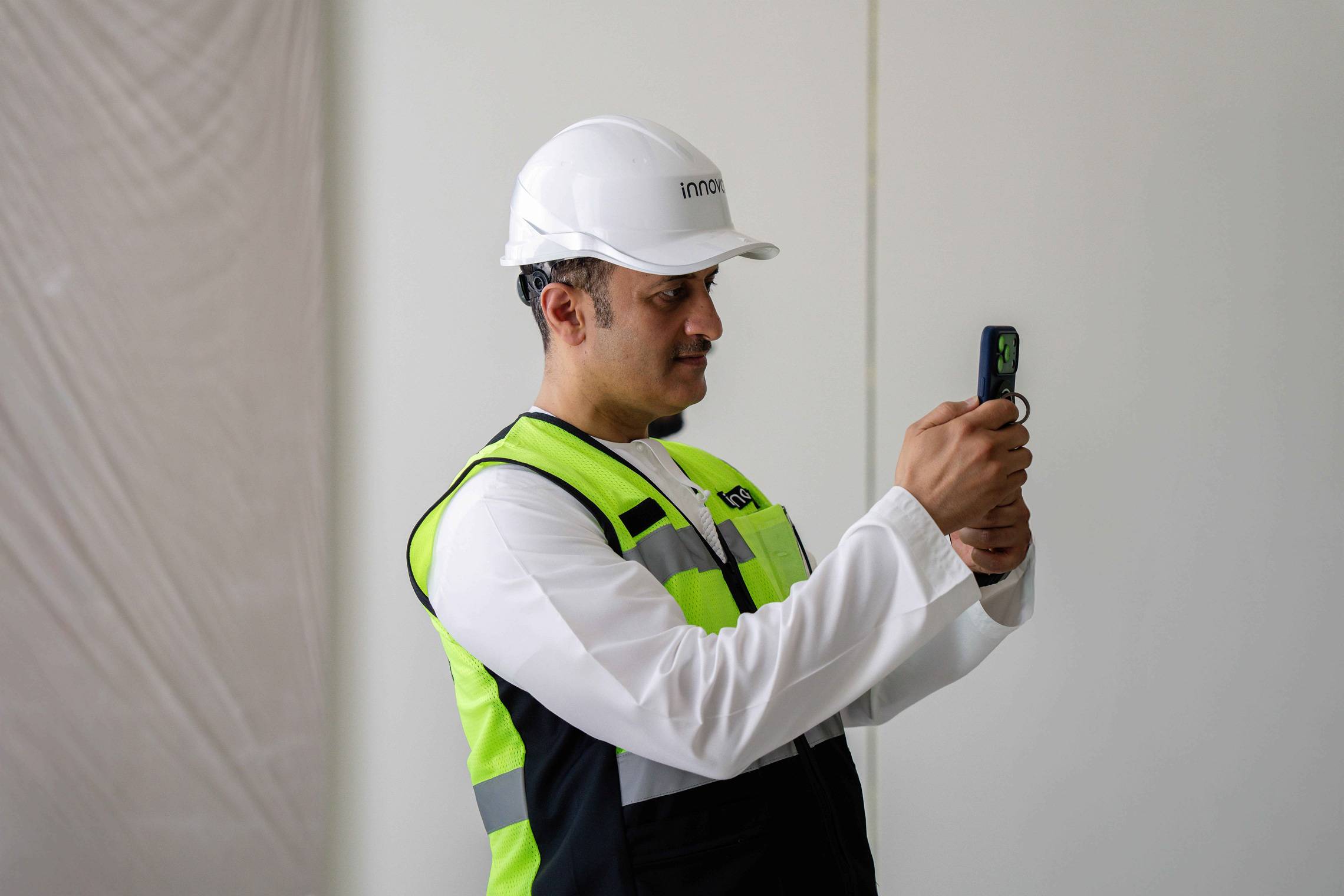 UAE official in hard hat photographs construction robotics at an Innovo site